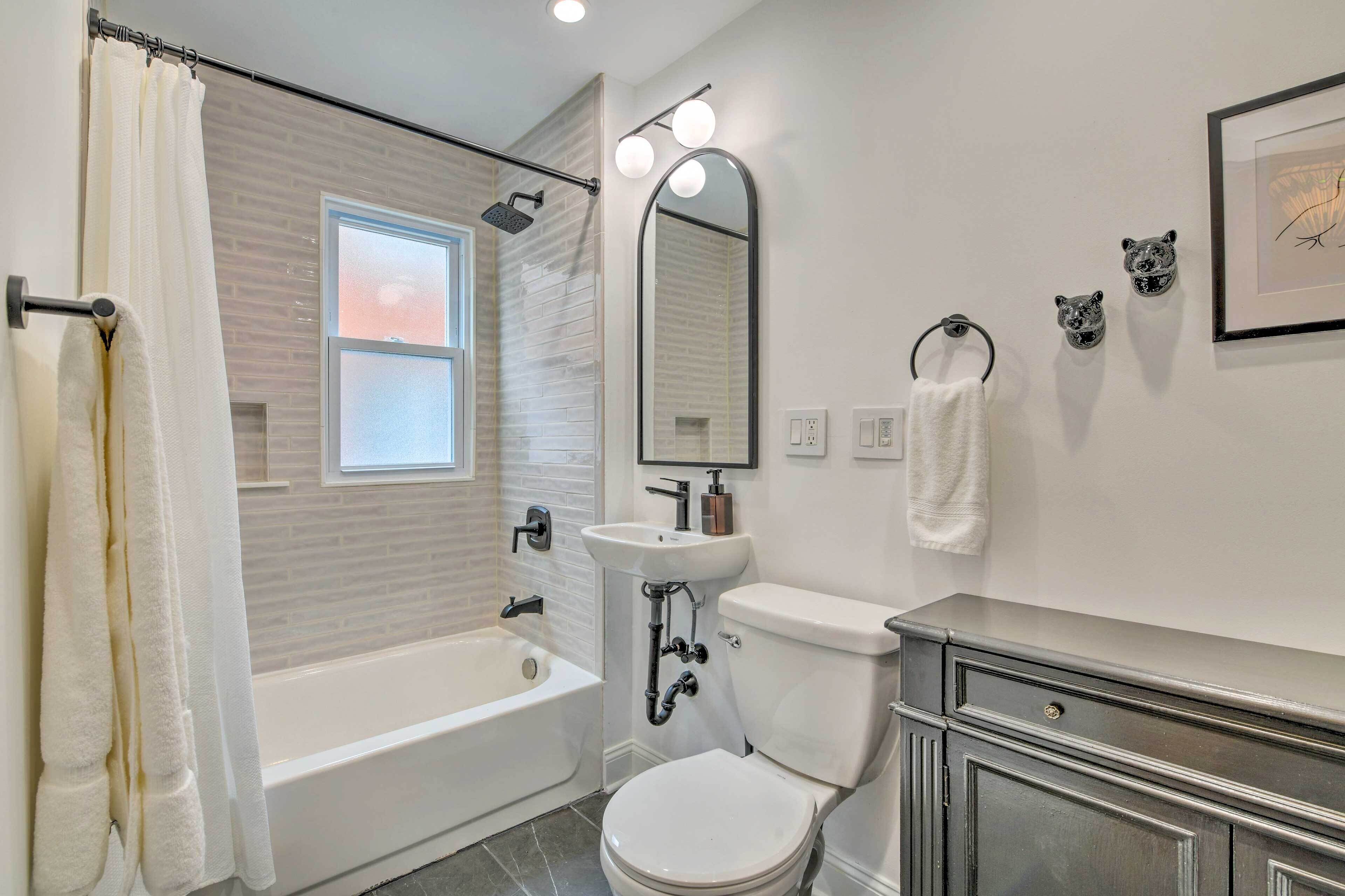 A modern bathroom with a bathtub, toilet, sink, and vanity.