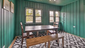 Comedor con mesa y sillas de madera, paredes con paneles verdes y piso estampado.