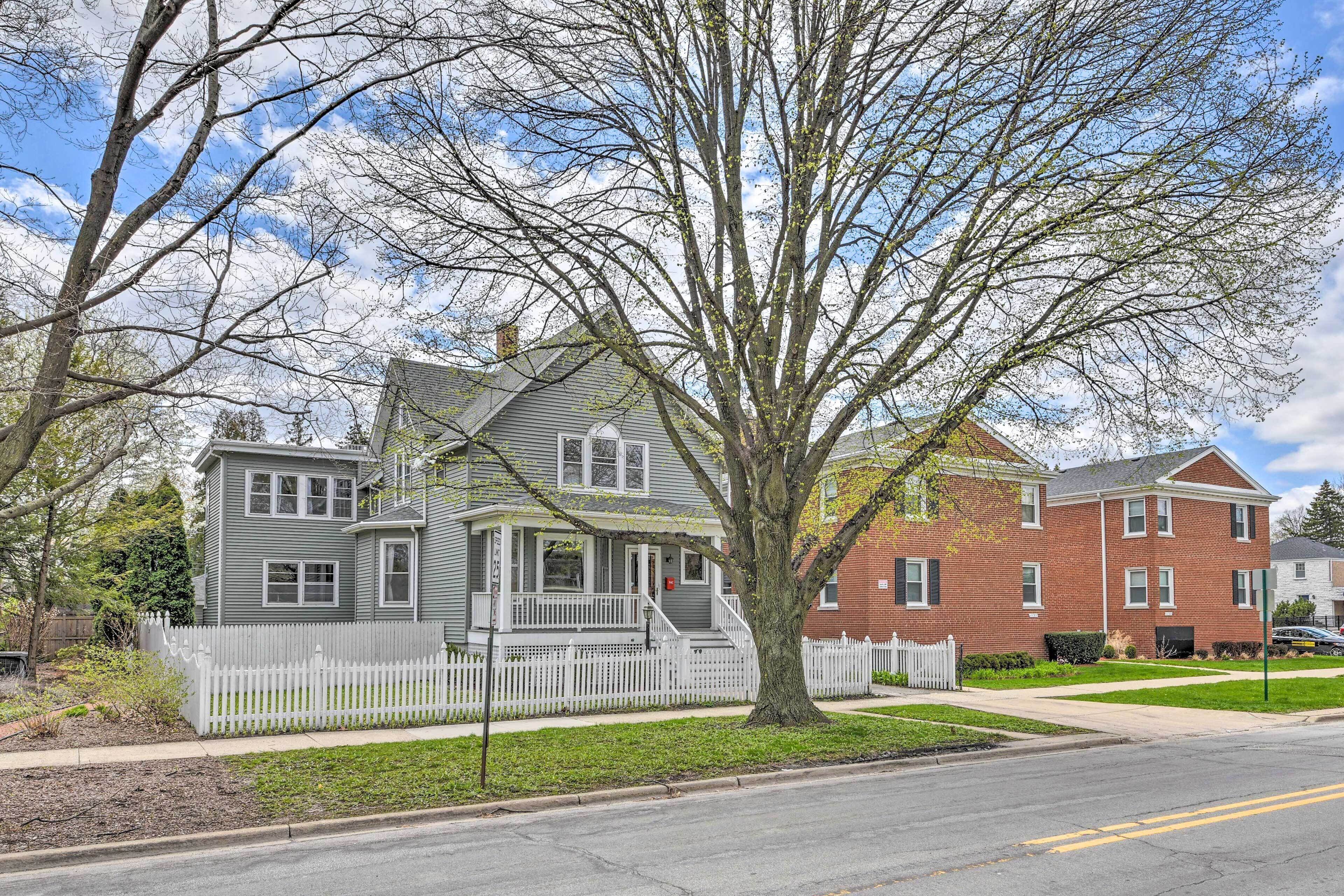 A two-story house with a porch and a white picket fence.