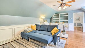 A living room with a blue sofa, yellow cushions, a small table with a plant, and a ceiling fan. - Pet-friendly Pond View Loft' w/ Private Pool! (Pine Bush)