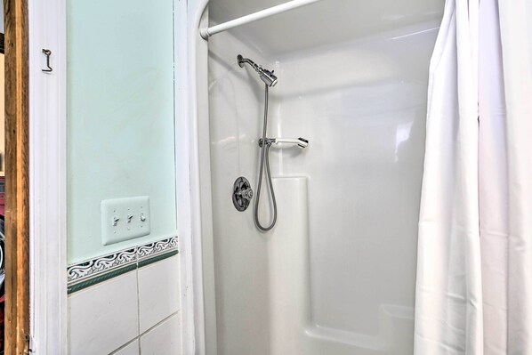 A bathroom with a shower, a white bathtub, and a white door. - Pet-friendly Pond View Loft' w/ Private Pool! (Pine Bush)