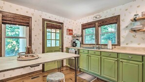 A kitchen with green cabinets, a white countertop, and a window with a view of trees. - Whimsical Bat Cave Cottage w/ Fire Pit! (Hendersonville)