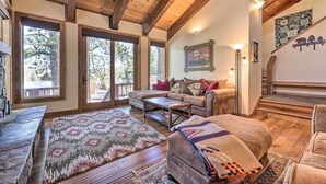 A cozy living room with a wooden ceiling, large windows, a sofa, a coffee table, and a fireplace. - Shuttle to Ski Resort: Northstar Home! (Truckee)