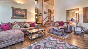 A cozy living room with a wooden staircase, leather sofas, and a decorative wall piece. - Shuttle to Ski Resort: Northstar Home! (Truckee)