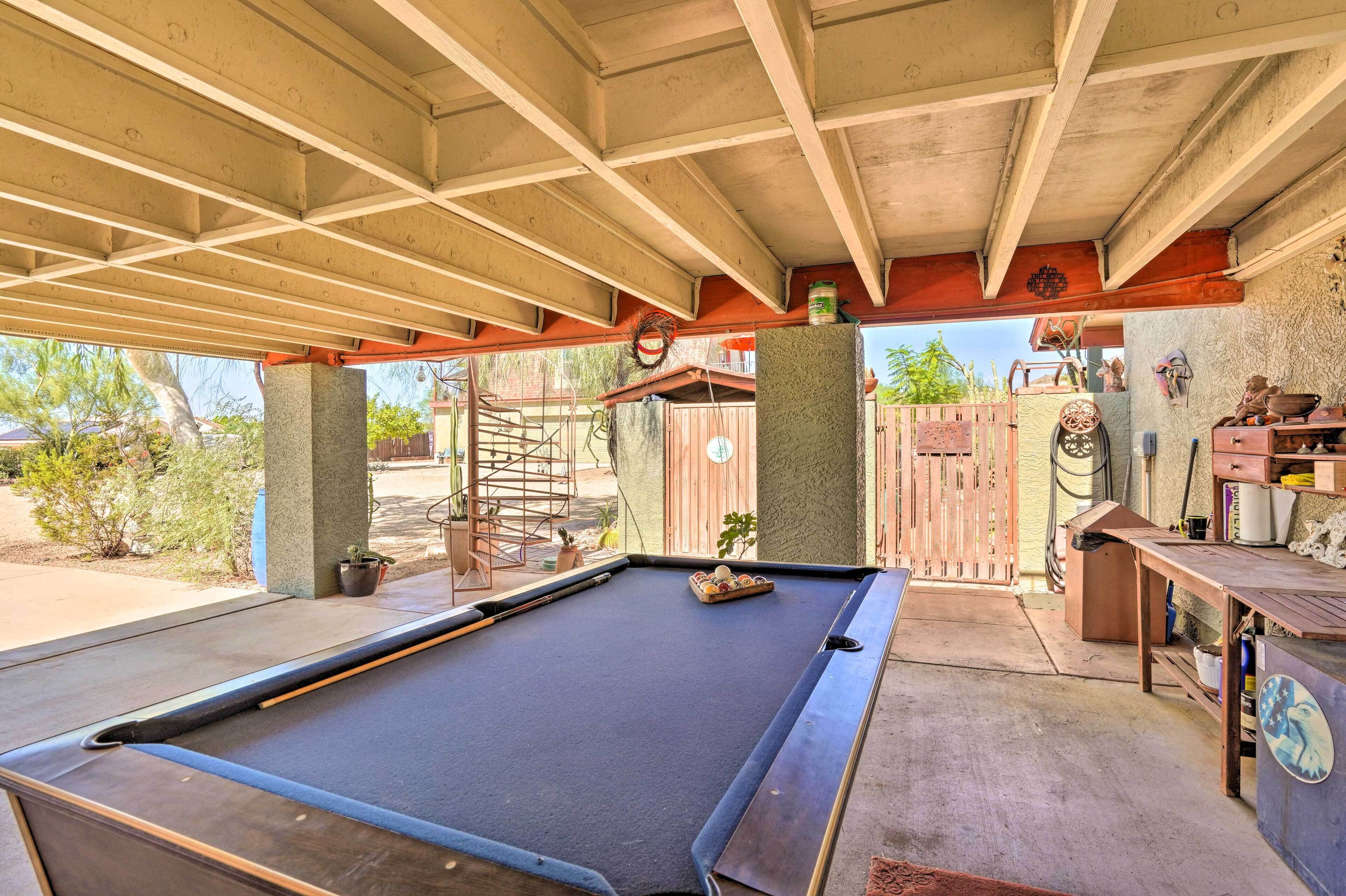 An indoor pool area with a pool table, a wooden bench, and a concrete pillar.