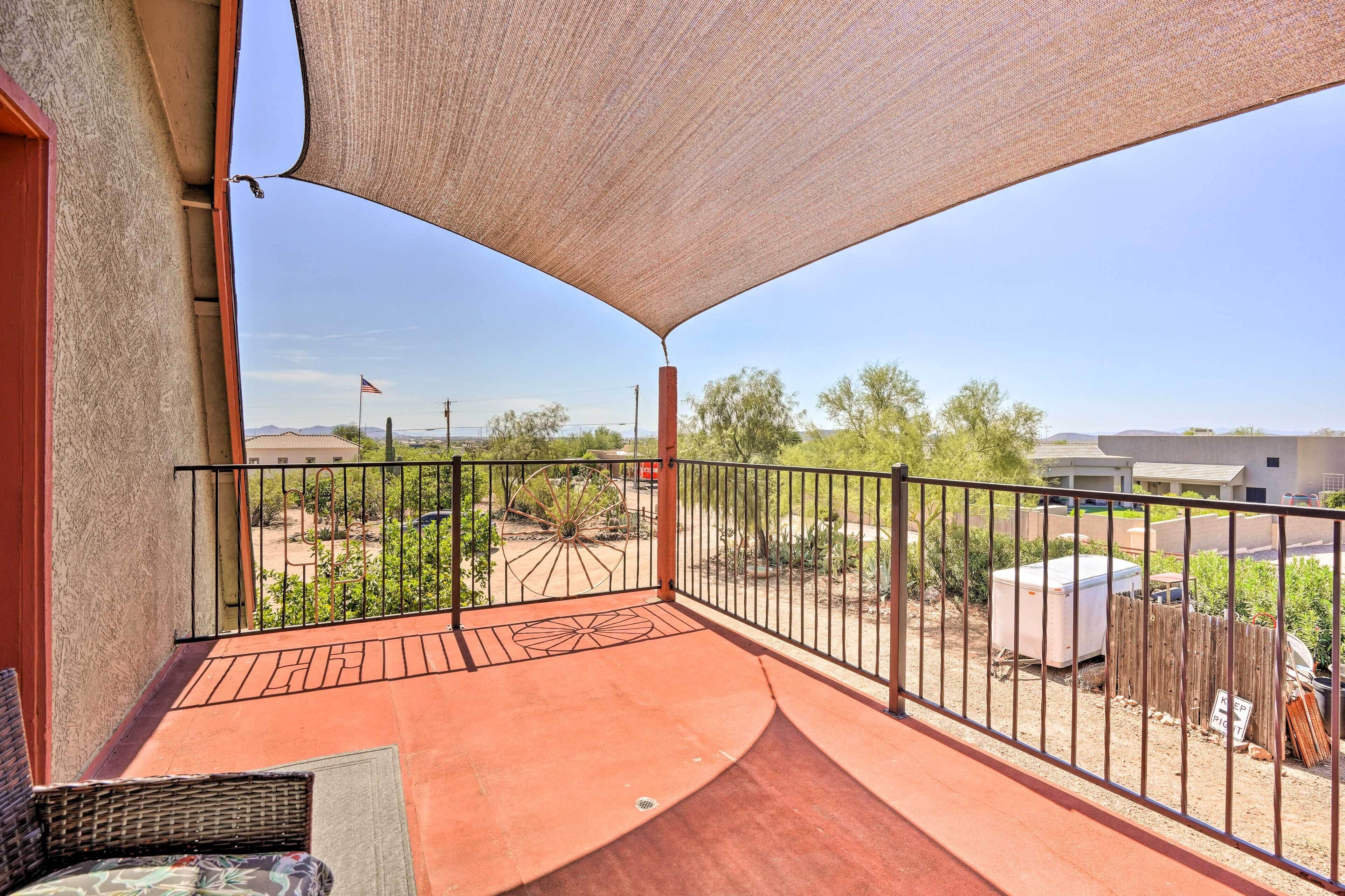 Un balcon avec vue sur un paysage désertique, un patio et une cour clôturée.