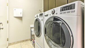 Uma lavanderia com duas máquinas de lavar de carregamento frontal e uma secadora.