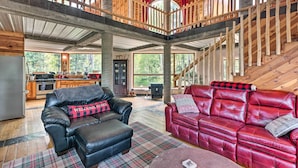 A spacious living area with a high ceiling, a wooden staircase, and a view of the outdoors. - Angel Fire Cabin w/ Deck ~ 2 Mi to Ski & Hiking! (Angel Fire)