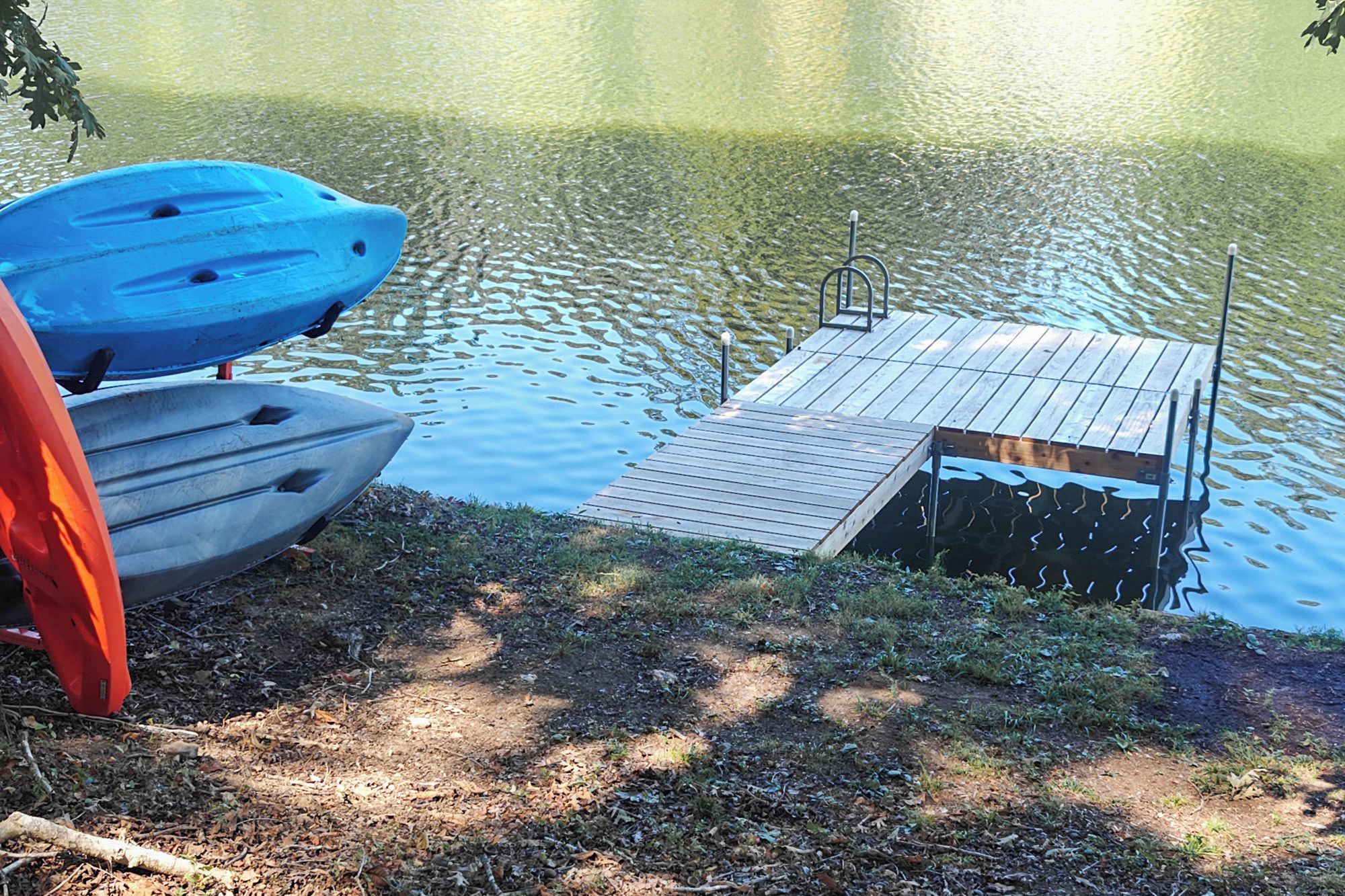 A wooden dock extending into a calm lake with a small platform at the end.