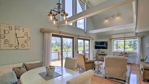 A spacious living room with a large dining table, comfortable seating, a chandelier, and large windows offering a view of the outdoors. - Lake House Haven: Fire Pit, Boat Dock + More! (Johnson City)