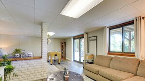 A living room with a sofa, ottoman, and a table with a foosball table. - Lake House Haven: Fire Pit, Boat Dock + More! (Johnson City)