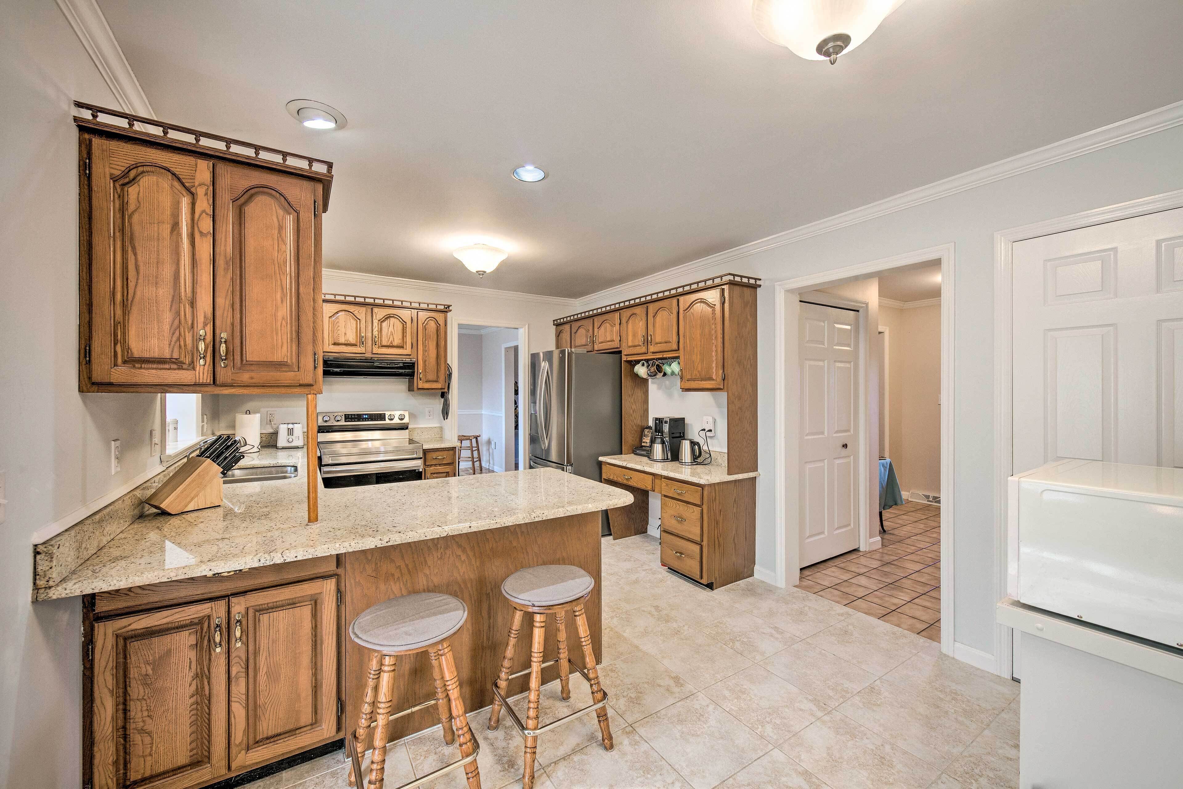 A kitchen with wooden cabinets, a granite countertop, and a stainless steel refrigerator.