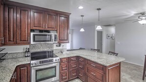 A kitchen with dark wood cabinets, stainless steel appliances, granite countertops, and pendant lighting. - Parker Home on the Colorado River w/ Views! (Parker)