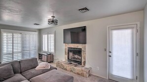 A living room with a stone fireplace, a gray sectional sofa, and a door with blinds. - Parker Home on the Colorado River w/ Views! (Parker)