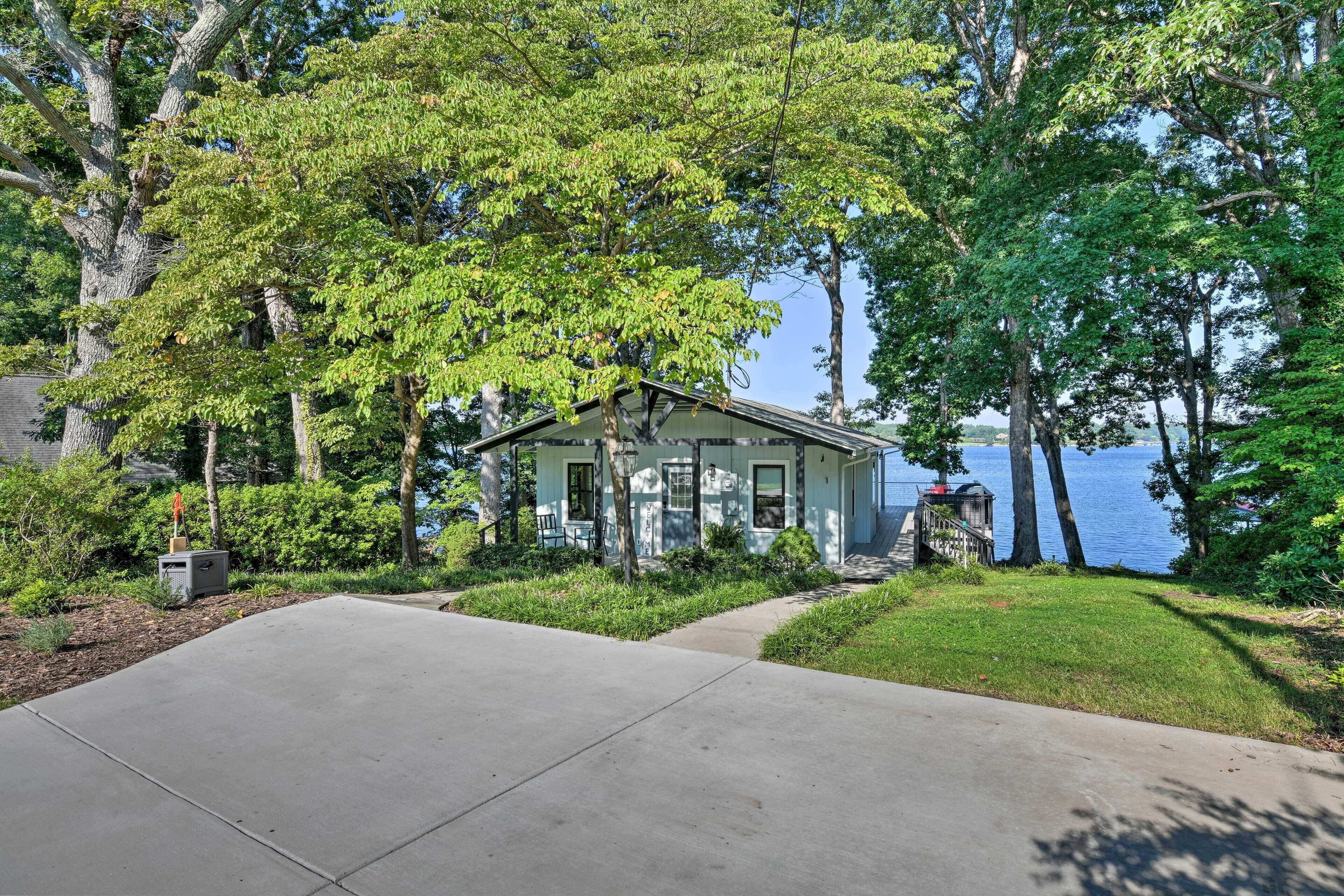 A house with a front yard, a driveway, and a view of a lake.