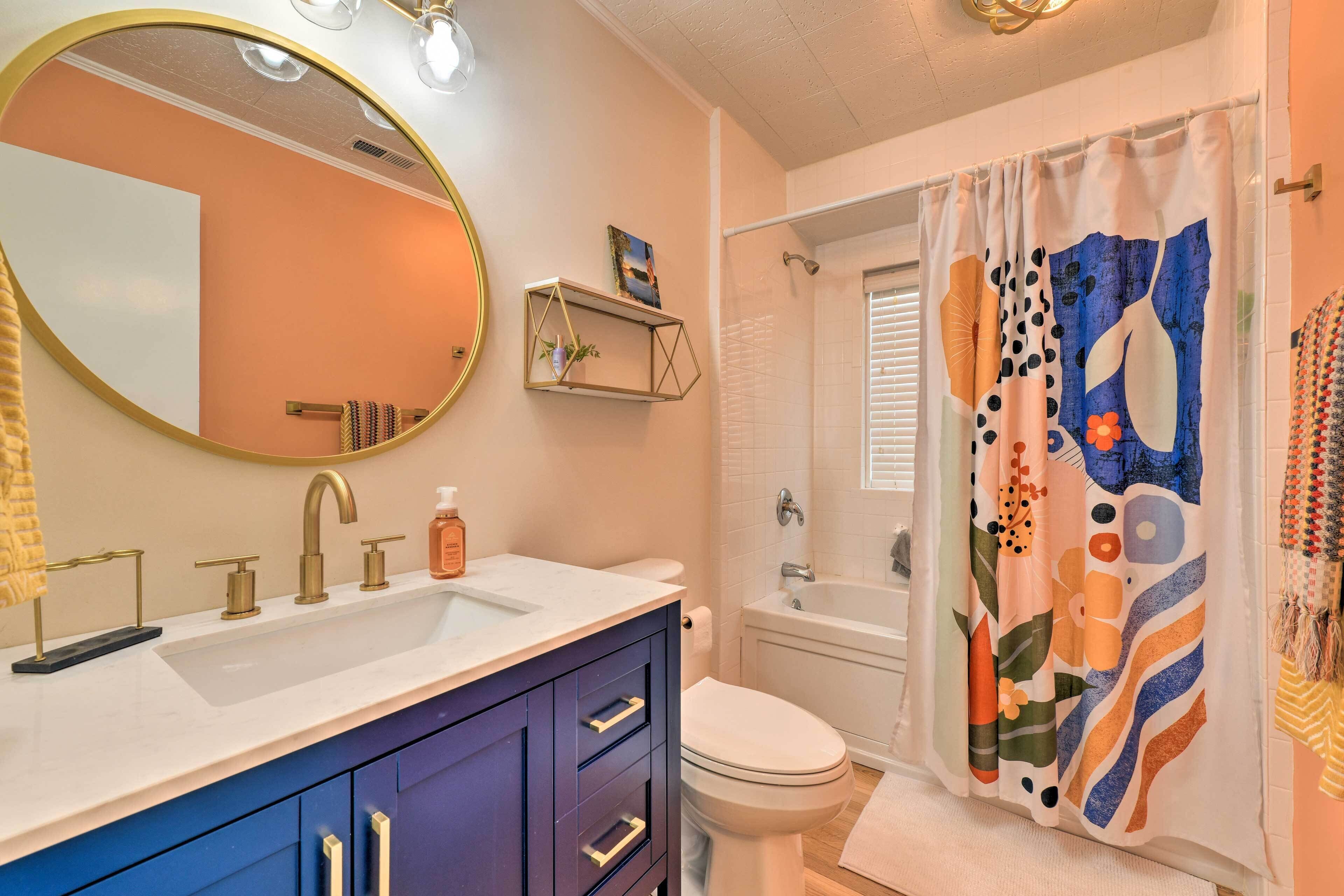 A bathroom with a vanity, sink, mirror, and toilet.