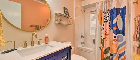 A bathroom with a vanity, sink, mirror, and toilet.