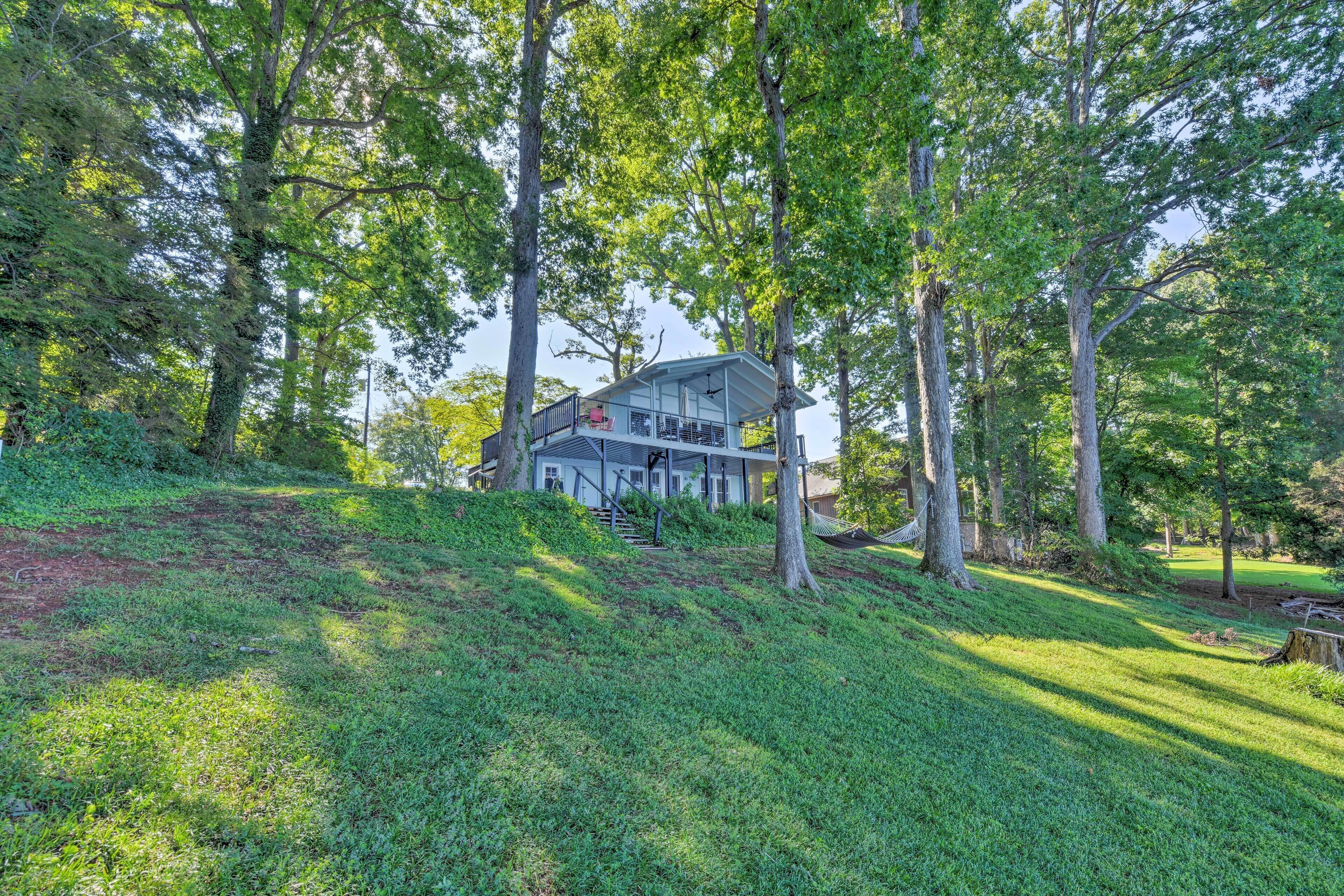 A house surrounded by trees with a covered porch and a staircase leading to the entrance.