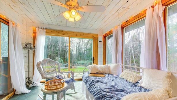 A cozy bedroom with a bed, a rocking chair, and a window overlooking a garden.