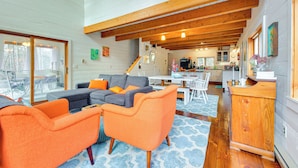 A spacious living area with a large sectional sofa, orange armchairs, and a wooden ceiling.