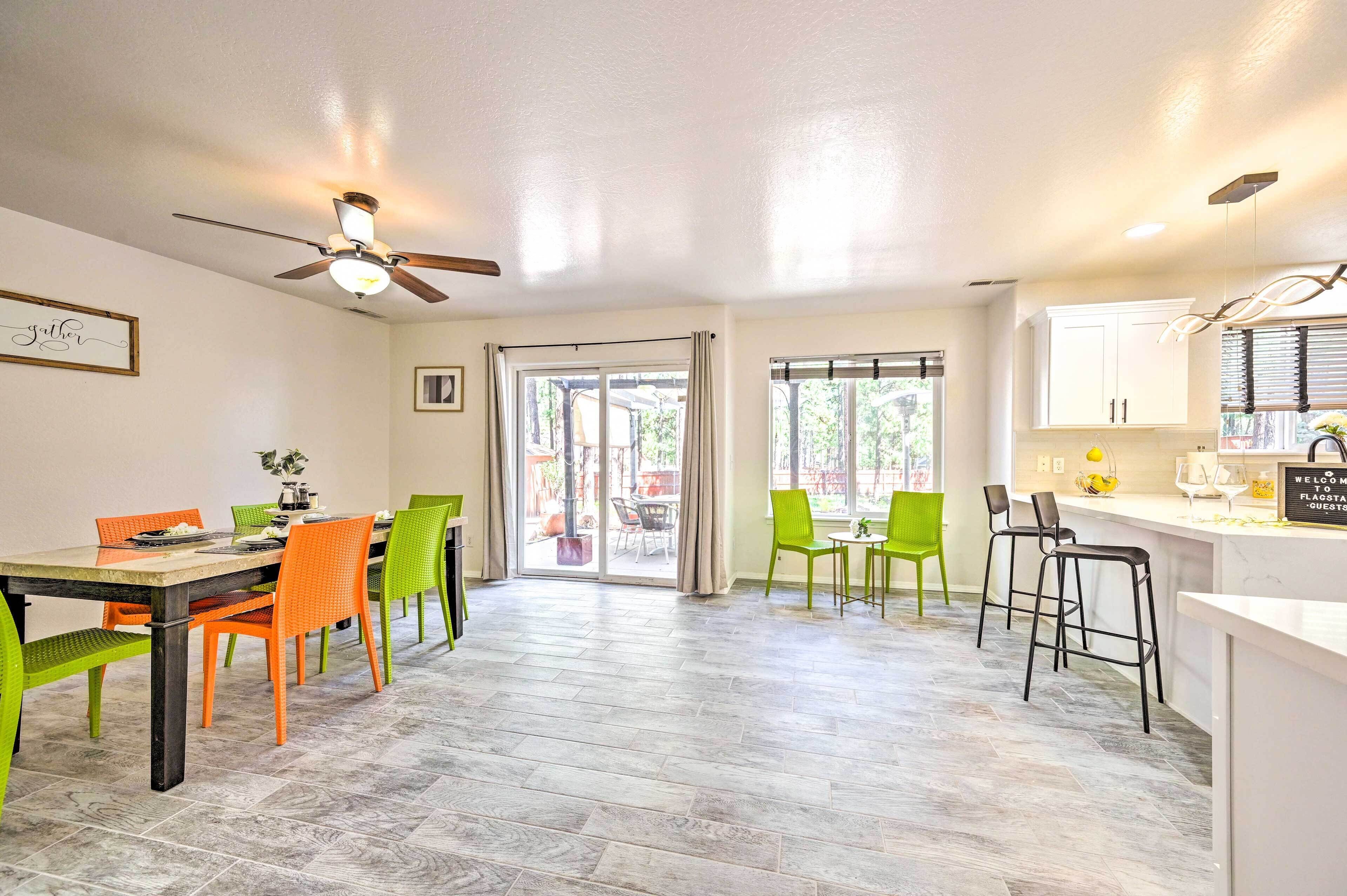A dining area with a table and chairs, a ceiling fan, and a view to the outside.