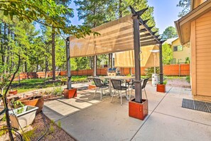 An outdoor patio with a covered seating area, a grill, and potted plants.