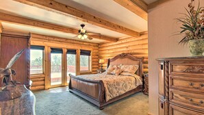 A log cabin bedroom with a bed, wooden dresser, and a ceiling fan. - Hot Tub, Game Room & Theater: Luxe Show Low Home (Show Low)