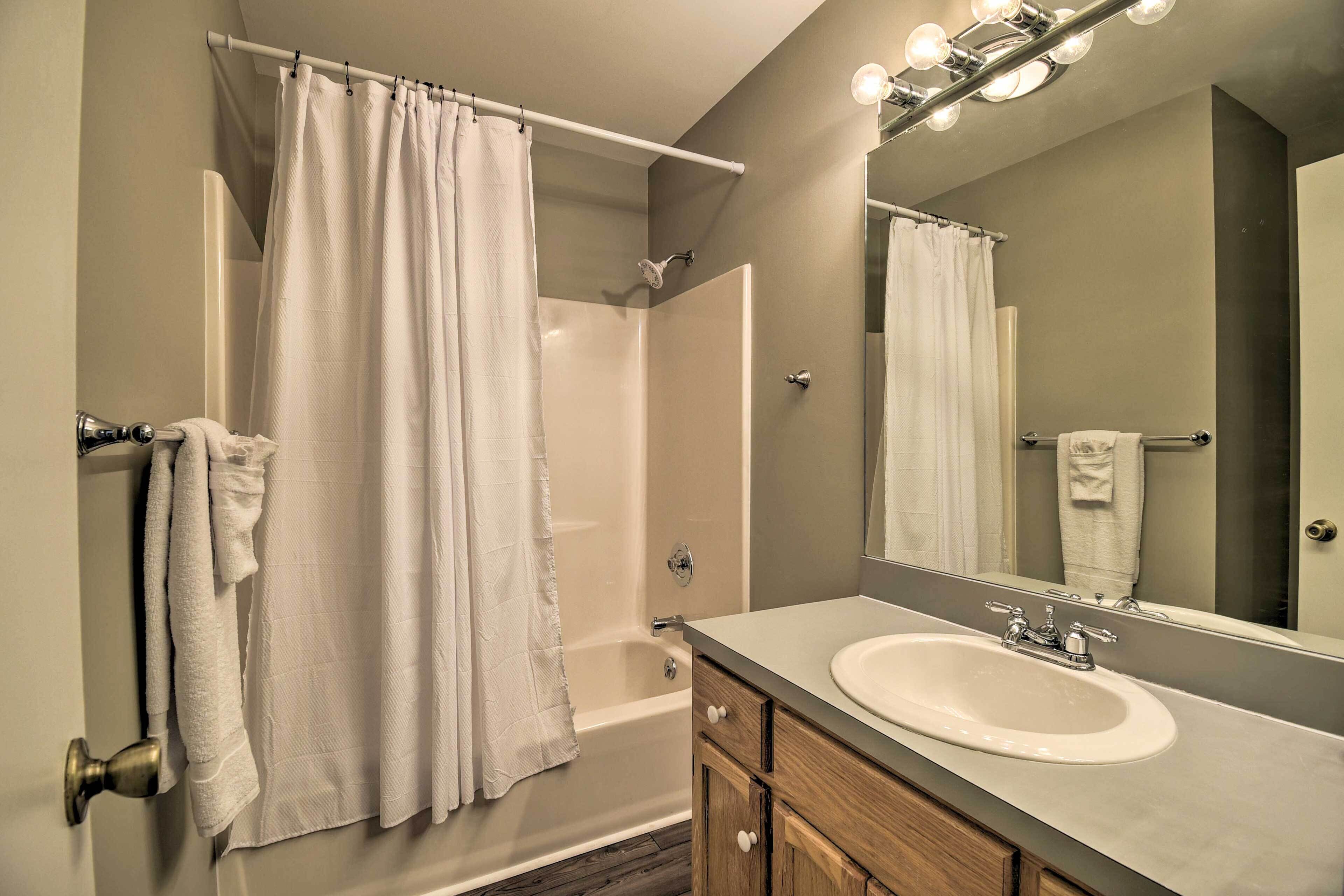A modern bathroom with a bathtub, shower, and sink.