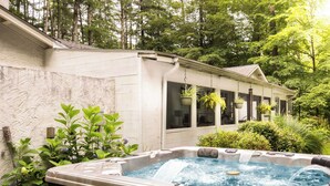 Un jacuzzi en un jardín, con una casa al fondo.