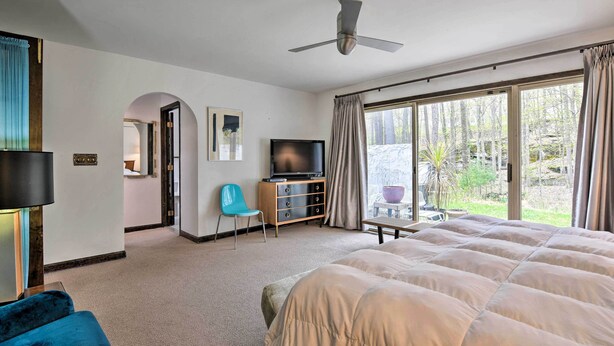 Una habitación de hotel con una cama grande, televisión, escritorio y vistas al exterior.