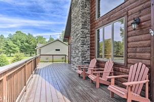 Una terraza de madera con sillas Adirondack, un pilar de piedra y un ventanal grande.