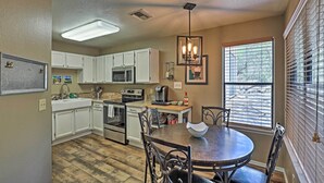 A kitchen with white cabinets, a dining table with chairs, a hanging light fixture, and a window with blinds. - Tucson Desert Retreat w/ Pool + Hot Tub Access! (Tucson)