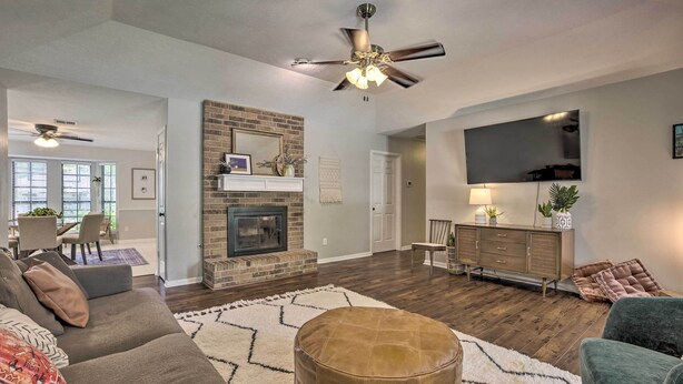 A spacious living room with a fireplace, a ceiling fan, a TV mounted on the wall, and a dining area visible through an open door. - Pet-friendly Bryan Home < 5 Mi to Texas A & M! (Bryan)