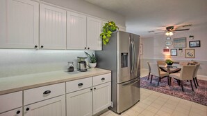 A kitchen with white cabinets, a stainless steel refrigerator, a coffee maker, and a dining area with a table and chairs. - Pet-friendly Bryan Home < 5 Mi to Texas A & M! (Bryan)