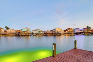 A waterfront property with a wooden dock, multiple colorful buildings, and a calm water body. - Snowbird Getaway: Waterfront Home, 1 Mi to Beach (Corpus Christi)
