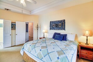 Ein Schlafzimmer mit einem großen Bett, einem Nachttisch mit Lampe, einer Tür zu einem anderen Raum und einem Wandbild.