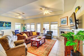 A spacious living room with a fireplace, comfortable seating, and large windows. - Snowbird Getaway: Waterfront Home, 1 Mi to Beach (Corpus Christi)