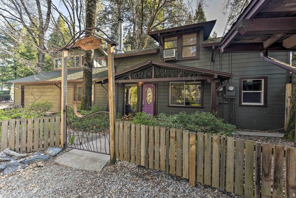 A two-story house with a wooden fence, a front door, and a sign that reads "The Cottage."