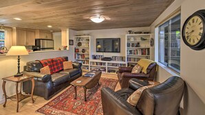 A cozy living room with leather sofas, a coffee table, and a bookshelf filled with books. - Peaceful Cottage w/ Grill & Yard in Grass Valley! (Grass Valley)