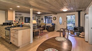A spacious kitchen with wooden cabinets, a dining area with a round table, and a cozy living space with a fireplace. - Peaceful Cottage w/ Grill & Yard in Grass Valley! (Grass Valley)