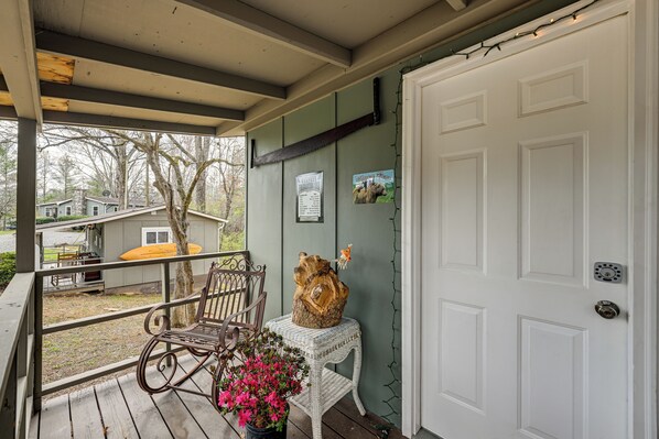 A porch with a rocking chair, a small table with a wooden sculpture, and a door with a mailbox and a poster. - Unwind w/ a Shared Hot Tub: Cozy Whittier Getaway (Whittier)