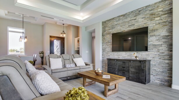 A modern living room with a stone fireplace, a large TV mounted on the wall, and a comfortable seating area with a sofa and a coffee table. - Picturesque Texas Gulf Coast Home in Port Isabel! (Port Isabel)