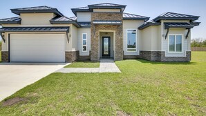 A modern two-story house with a garage, a stone accent wall, and a well-maintained lawn. - Picturesque Texas Gulf Coast Home in Port Isabel! (Port Isabel)