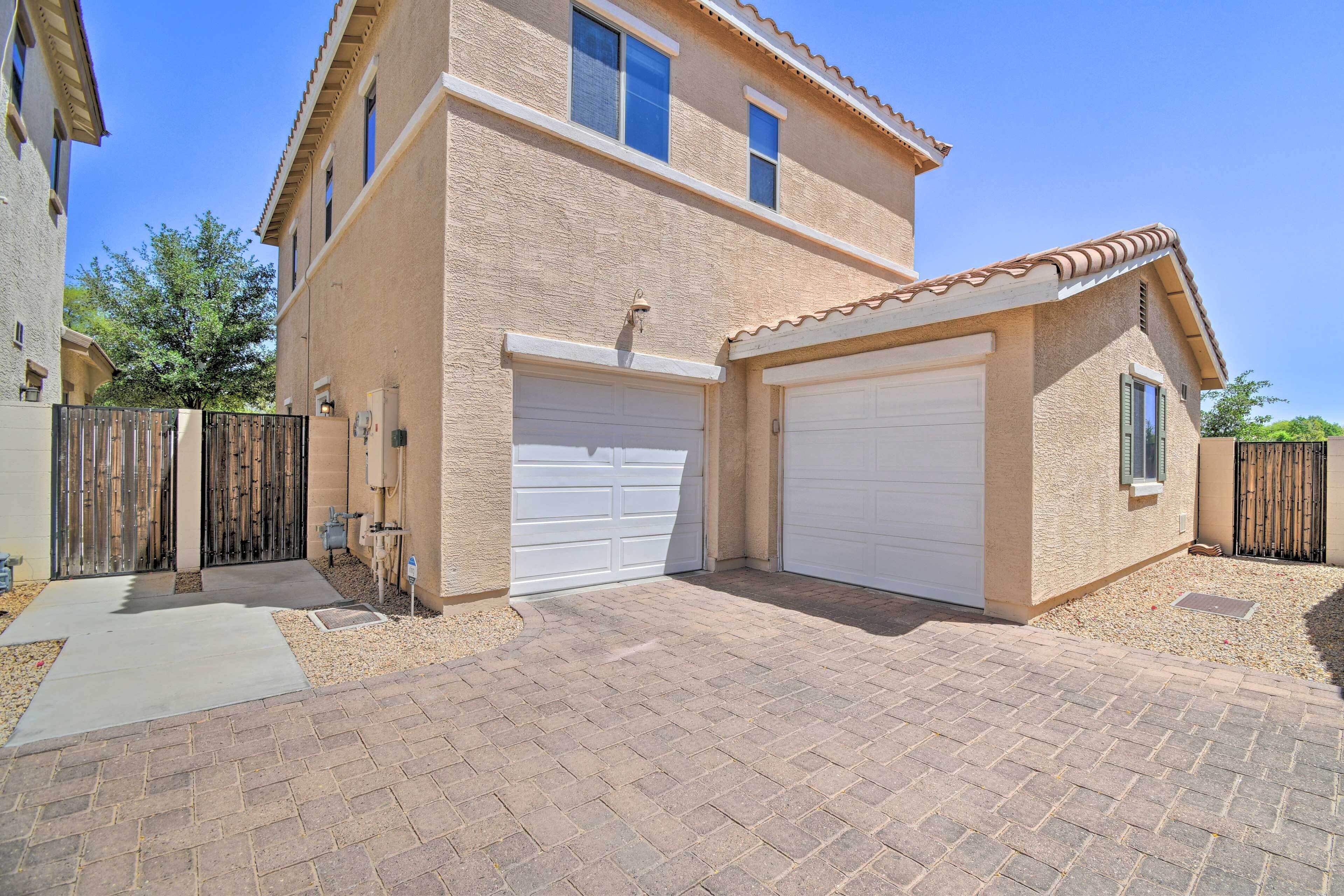 A two-story house with a garage, a paved driveway, and a small garden area.