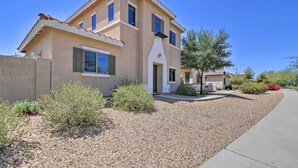 A two-story house with a beige facade, a tiled roof, and a gravel driveway. - Goodyear Escape w/ Grill: Community Pool Access! (Goodyear)