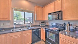 A modern kitchen with wooden cabinets, a stainless steel sink, a microwave, a toaster, and an oven. - Goodyear Escape w/ Grill: Community Pool Access! (Goodyear)