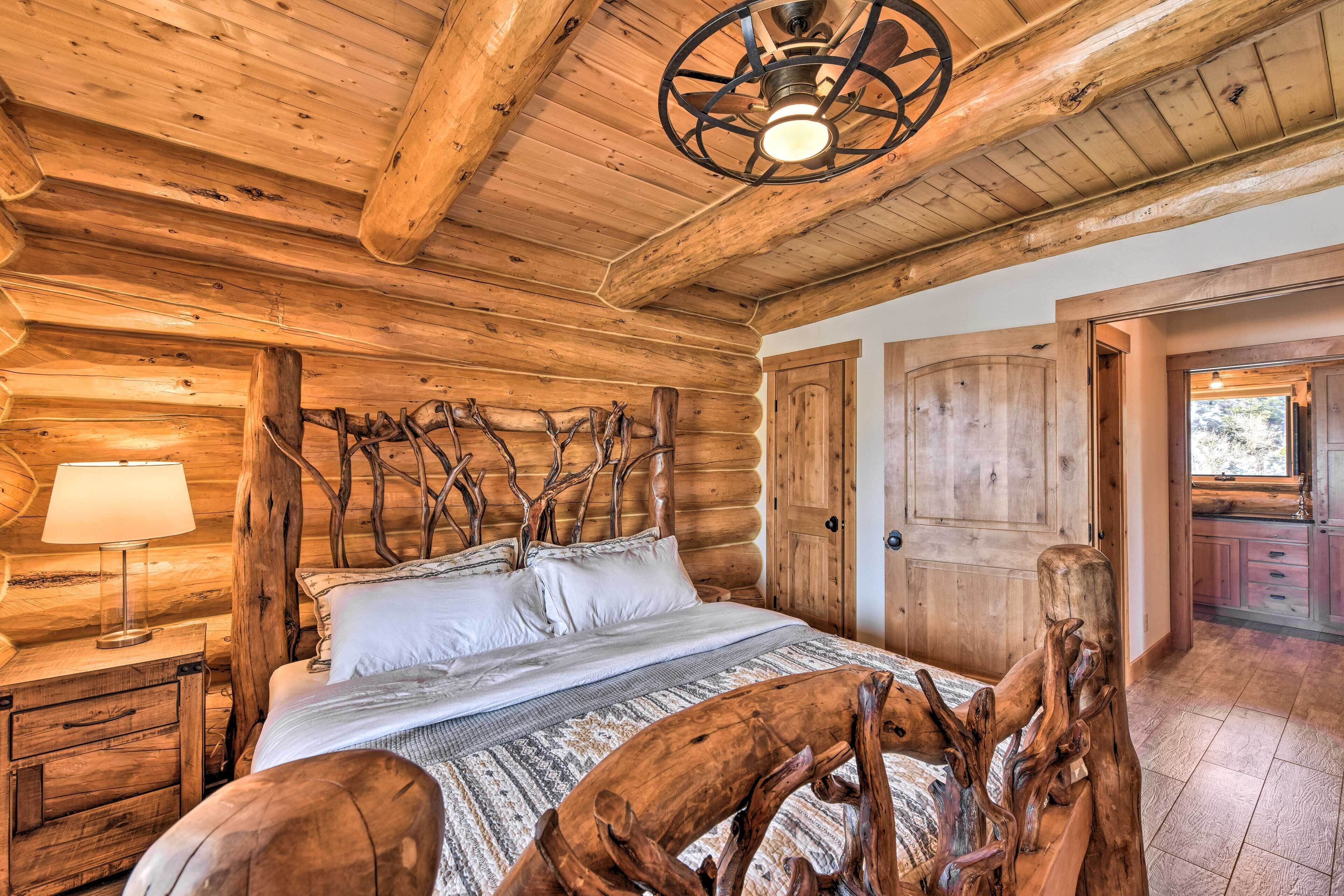 A log cabin bedroom with a wooden bed, a nightstand, a lamp, and a rustic decor piece.