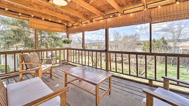 A covered outdoor deck with wooden furniture and a view of the surrounding landscape.