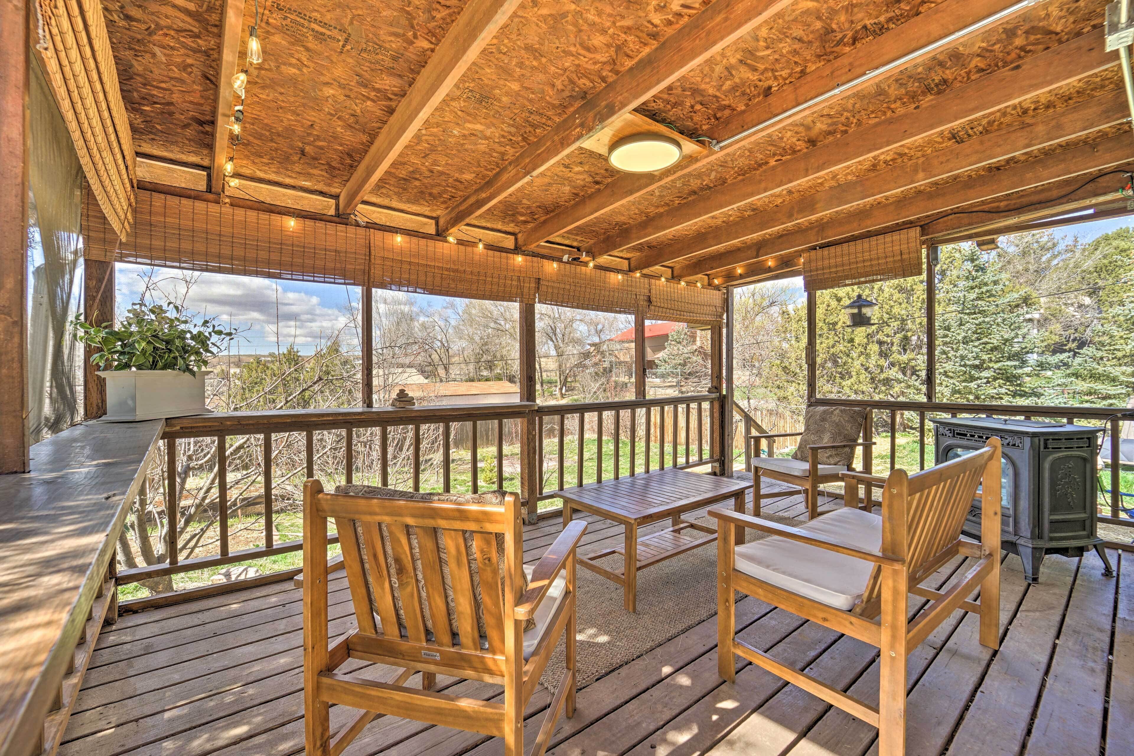 A wooden deck with outdoor furniture, large windows, and a view of the surrounding landscape.