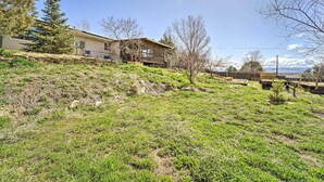 A residential property with a sloped landscape, a wooden deck, and a view of the surrounding area.